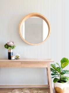 a wooden table sitting next to a mirror and potted plant