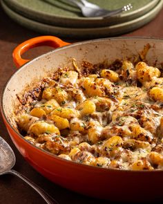 a casserole dish with potatoes and meat in it on a wooden table next to utensils