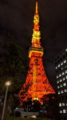 the eiffel tower lit up in red and yellow at night with buildings around it