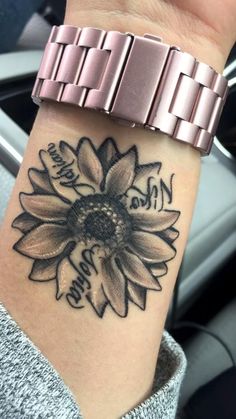 a woman's wrist with a sunflower tattoo on it