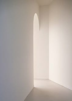 an empty room with white walls and light coming in from the window on the far wall