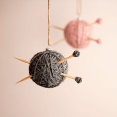 two balls of yarn and knitting needles hanging from strings