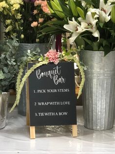 a sign that is sitting in front of some potted plants and other flowers on a table