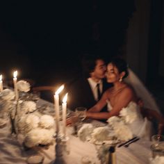 a bride and groom sitting at a table with candles