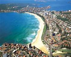 an aerial view of a city next to the ocean with buildings on both sides and blue water