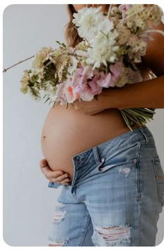 a pregnant woman with flowers in her belly and jeans on the bottom half of her stomach