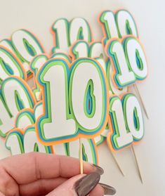 a hand holding a toothpick in front of a number ten cake topper