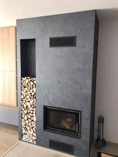 a fire place in the middle of a room with wood stacked on top of it