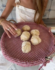 a woman in white shirt holding a red and white checkered plate with cookies on it