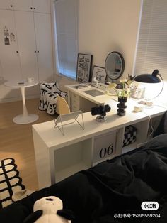 a white desk with black and white decor in a living room next to a bed