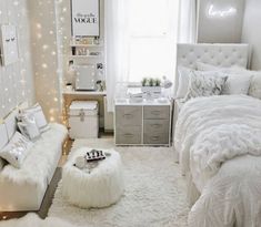 a bedroom decorated in white and gray with lights on the walls, bedding, rugs and pillows