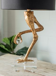 a wooden table lamp with a black shade on it and a gold monkey figurine