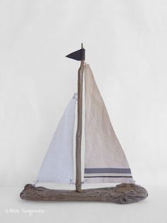 a wooden sailboat with white gump on it's side and the caption says driftwood sailboat 2?