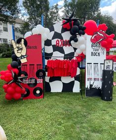 some red and black balloons are on display in the grass with other decorations around them