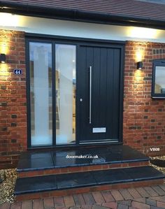 a black front door with two sidelights on the brick wall and steps leading up to it