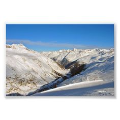 a snowy mountain range with skiers on the snow and blue sky in the background