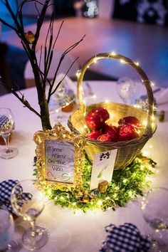 a table topped with a basket filled with apples next to a sign that says wedding date