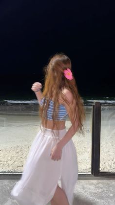 a woman with long red hair walking on the beach