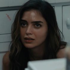 a woman with long hair is staring at the camera in front of white cabinets and cupboards