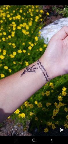 a person's arm with a tattoo on it and yellow flowers in the background