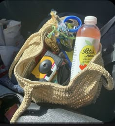 a basket filled with assorted items sitting on top of a car seat next to a bottle