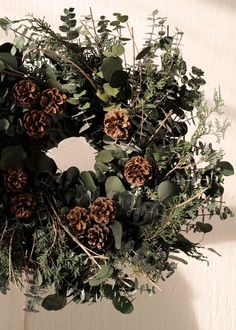 a wreath with pine cones and greenery