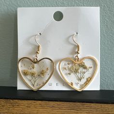 two heart shaped earrings with dried flowers on them