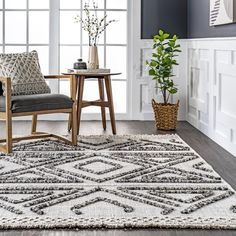 a living room with a rug, chair and potted plant on the table in front of it