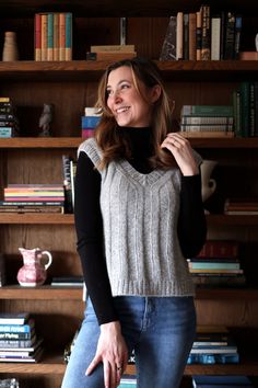 a woman standing in front of a bookshelf with her hand on her hip