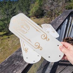 a person holding up two white and gold snowboards on top of a wooden deck