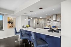 a kitchen with blue chairs and an island in front of the counter top is shown