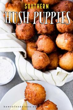 fried hush puppies on a white plate with lemon wedges and ranch dressing in the background