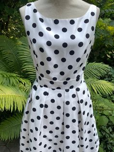 "Okay, first of all, it's washable and it has pockets! White poly with black polka dots makes this timeless piece so cheerful.  It's completely lined, and the bottom 10\" of the lining has an attached band of crinoline. There's a 7\" vee-dip in the back and then a 13\" zipper.  2\" waistband sits on the natural waist. Bust 34\" Waist 30\" Length 16\" to waist; 39\" in total" Casual Polka Dot Dress For Garden Party, Casual Garden Party Dress With Polka Dot Pattern, Summer Polka Dot Dress With Pockets, Casual Polka Dot Dress With Pockets, Polka Dot Sleeveless Lined Dress, Polka Dot A-line Lined Dress, Vintage Knee-length Polka Dot Dress, V-neck Polka Dot Mini Dress For Summer, Polka Dot V-neck Sundress