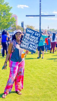 a woman holding a sign in the middle of a field