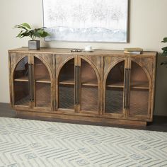 a wooden entertainment center with glass doors on the front and bottom, in a living room