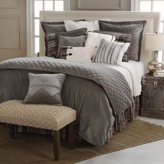 a bed with grey and white comforters in a bedroom