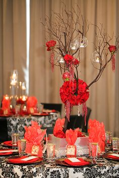 the table is set with red flowers, candles and place settings for an elegant dinner