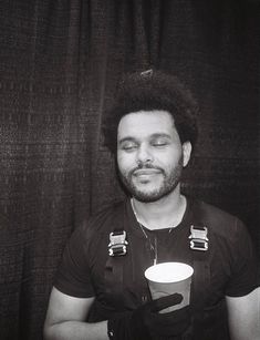 a black and white photo of a man with his eyes closed holding a coffee cup