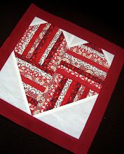 a red and white quilted table topper on a black surface with the center piece folded in half