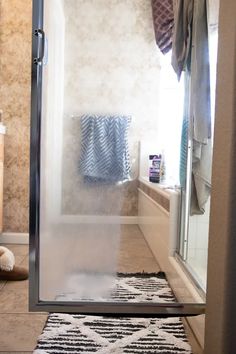 a bathroom with a shower and rugs on the floor in front of it's glass door