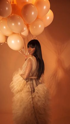 a woman in a white dress holding balloons