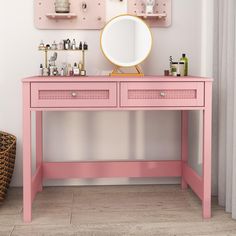 a pink vanity with two drawers and a mirror on it's side, next to a wicker basket