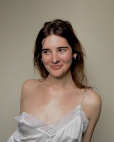 a woman in a white dress smiling at the camera with her nose piercings on