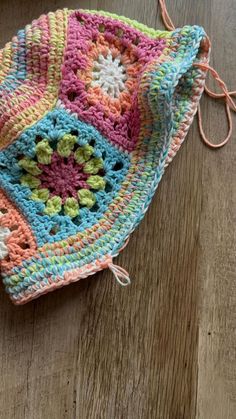 a colorful crocheted bag sitting on top of a wooden floor next to a pair of scissors