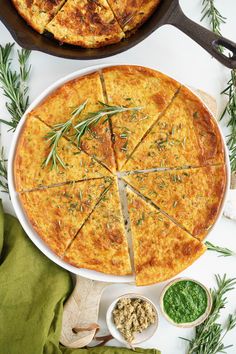 two pizzas with cheese and herbs on the top, one is cut into slices