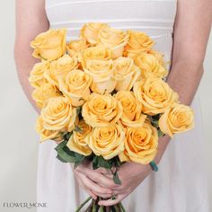 a woman holding a bouquet of yellow roses