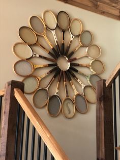 a clock made out of tennis rackets mounted to the side of a stair case