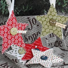 three star ornaments hanging from a christmas tree