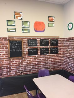 a brick wall in a classroom with chalkboards on the walls and purple chairs around it