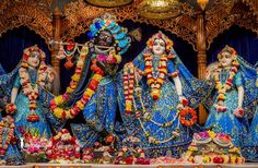 three statues of hindu deities in front of a stage with flowers and decorations on it